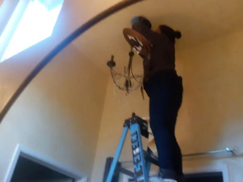 Electrician installing a chandelier in a Macclenny residence